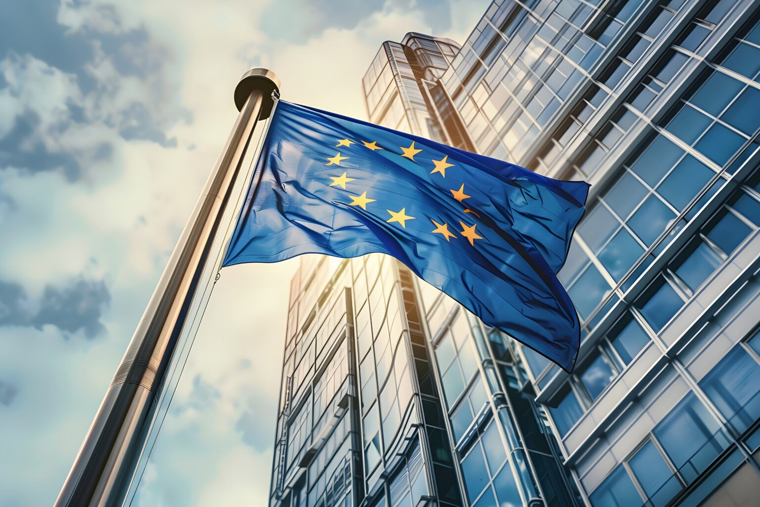 Flag of European Union waving in the wind in front of the modern parliament building on sunny day.