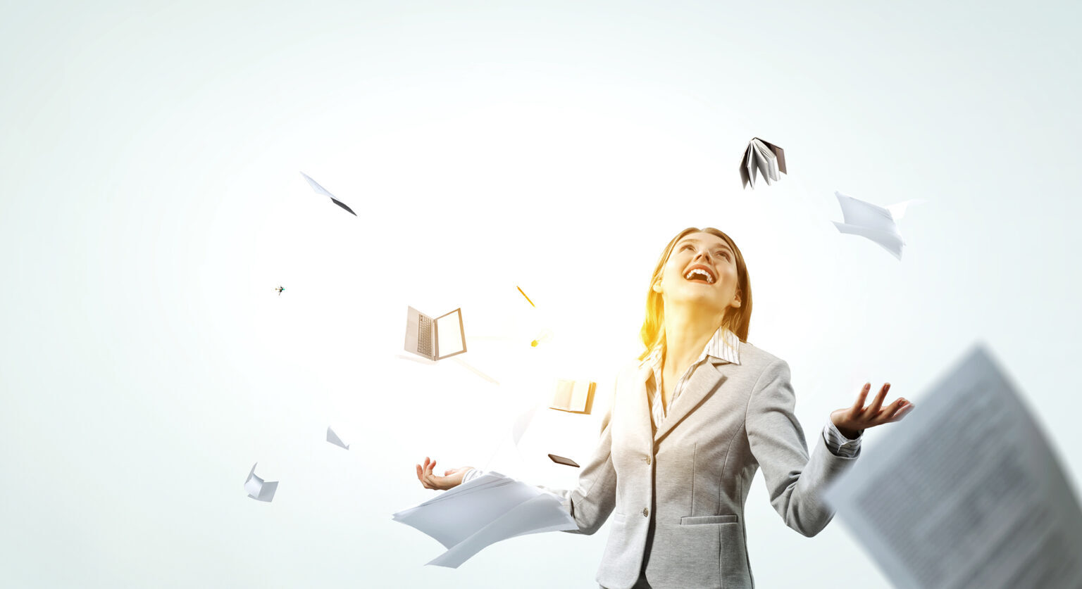 Woman in a suit throwing papers in the air joyfully