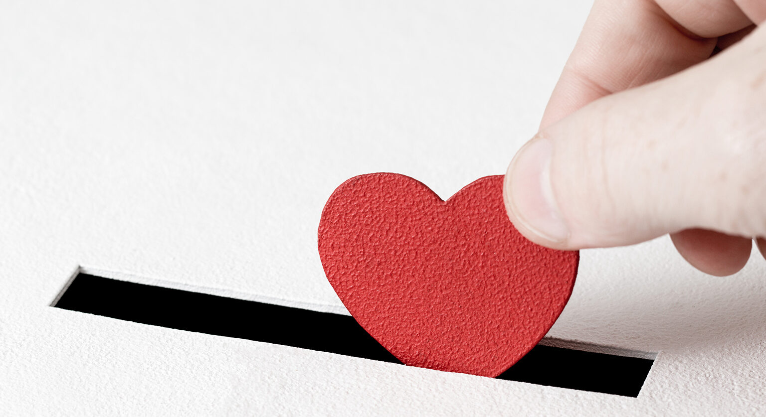 Someone sliding a small heart into a coin slot
