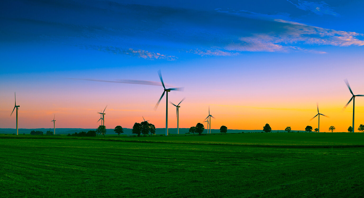 Windmills in a field against a sunset