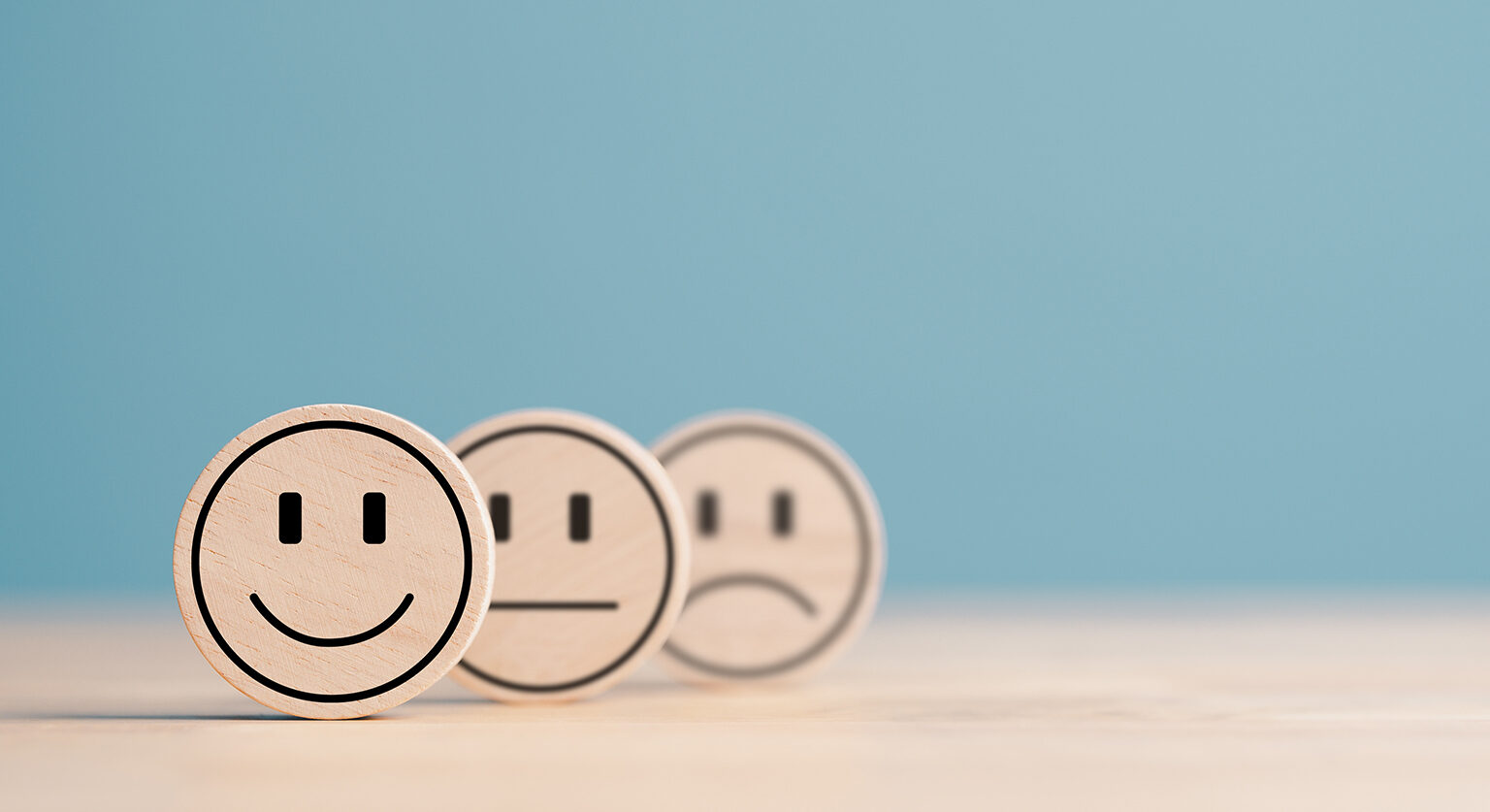 Three drawn faces in a row: one with a smile, one with a neutral look and one with a frown