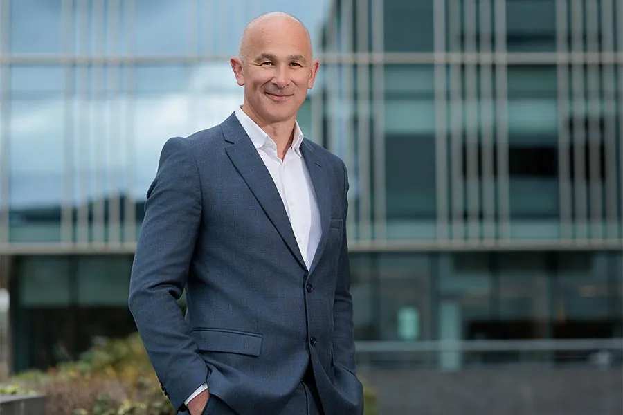 Mark Butler, Managing Partner of HLB Nathan, pictured in a business suit with his hands in his pockets in an outdoor location.